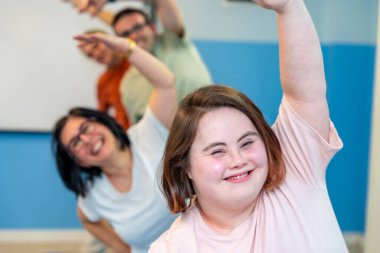 Happy group of people with special needs enjoying gymnastics stretching the back together clipart