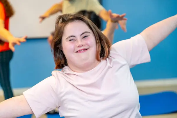 Woman with down syndrome smiling at camera while exercising in the gym