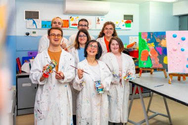 Portrait of a class painting group with white coats with mental disabled people clipart