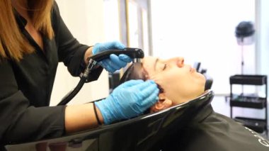 Kafkasyalı bir yetişkinin yakın çekimde saçlarını bir kuaförde yıkarken rahatlaması.