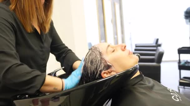 美容室でシンクで女性の髪を洗うスタイリスト — ストック動画