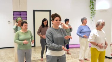 Hareket halindeki kadınlar Qi Gong sınıfını kapatırken belirli bir hareketle kapatıyor.