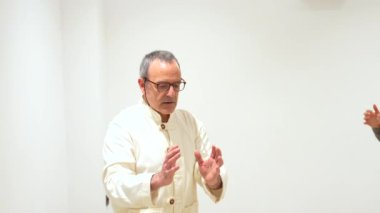 Qi gong erkek, olgun bir öğretmen. Bir sınıf dolusu olgun kadını kapalı bir merkezde yönetiyor.