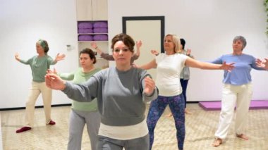 Yetişkin ve Kafkas sportif kadınlar, qi gong dersi sırasında kollarını açarlar.