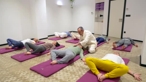 床にマットの上に横たわる複数の女性とQiongクラスで呼吸練習を指導するインストラクター — ストック動画