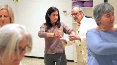 Qi Gong sınıfındaki olgun kadınlar koordineli hareket eden egzersizleri koreografiye alıyorlar.
