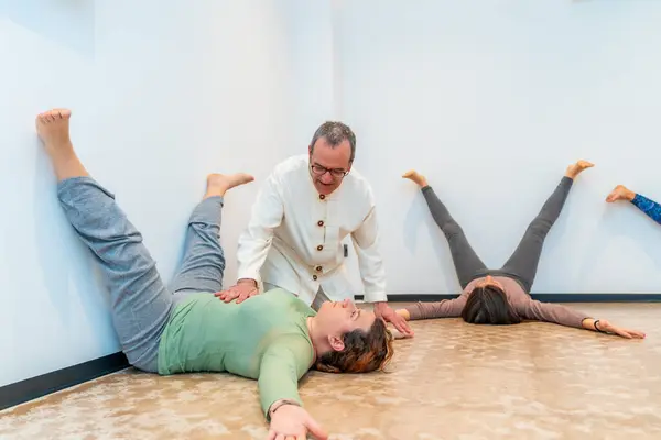Women performing a breathing exercise on the floor with the guidance of a Qi gong instructor