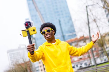 African cool and young streamer recording on online video using mobile in the city clipart