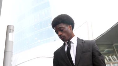 Afrikalı işadamı, bir finans bölgesinde, sokakta cep telefonu taşıyan bilgisayarla konuşuyor.