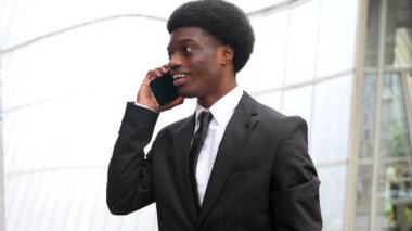 Sokakta işe giderken cep telefonuyla konuşan Afrikalı işadamı.