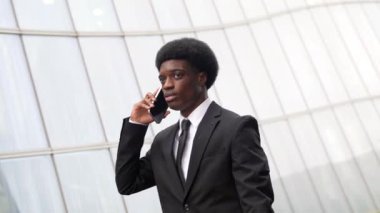 Afrikalı işadamı, mali bir bölgede ofisten çıkarken telefonla konuşuyor.