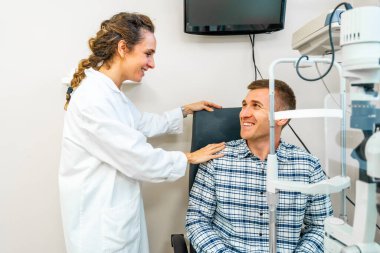 Friendly female optometrist comforting a patient during a check up in the clinic clipart