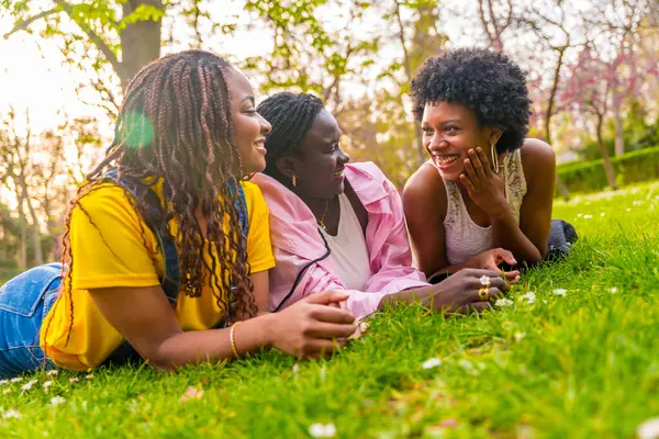 Onnellinen Kolme Nuorta Afrikkalaista Amerikkalaista Naista Makaa Puistossa Nauttimassa Keväästä tekijänoikeusvapaita valokuvia kuvapankista
