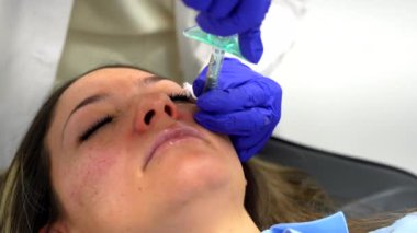 Doktor, gençleştirme güzellik prosedürü sırasında bir kadının yüzüne hiyalürik asit enjekte ediyor.