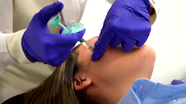 美容院の女性の顔にヒアルロン酸を投与する認識できない女性化粧品学者の高層ビュー — ストック動画