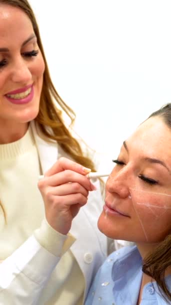 美容师医生在美容师诊所的一名妇女的脸上划上矫正线 — 图库视频影像