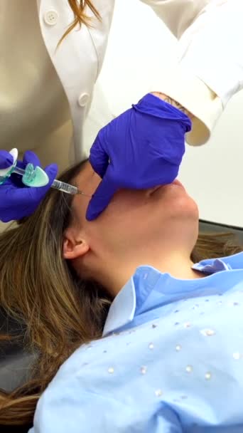 ヒアルロン酸を投与する前に患者の顔に綿パッドで注射領域を清掃する医師 — ストック動画