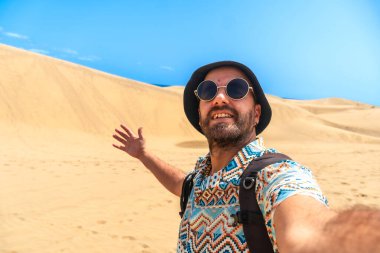 Gözlüklü ve şapkalı bir turistin selfie 'si Maspalom, Gran Canaria, Kanarya Adaları' nın kumullarında eğleniyor.