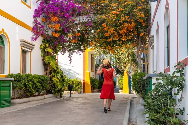 Yazın Gran Canaria 'daki Mogan kasabasında çiçeklerle dolu kırmızı elbiseli bir turist kadın. İspanya