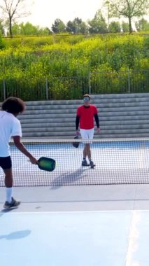 Açık hava sahasında Pickleball oynayan dört farklı etnik gruptan oluşan bir grubun tam boy fotoğrafı.