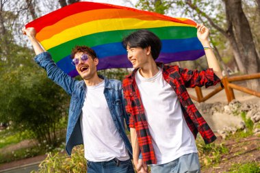 Parkta lgbt gökkuşağı bayrağı sallayan mutlu çoklu etnik arkadaşlar