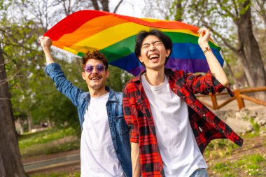 Parkta lgbt gökkuşağı bayrağı sallayan mutlu çokuluslu gay insanların portresi