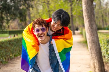 lgbt bayrağını parka saran çok ırklı eşcinsel erkekler.