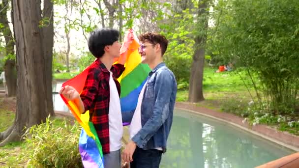 多族同性恋夫妇在公园庆祝多元文化的低视角旗帜 — 图库视频影像