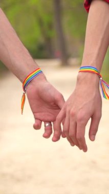 Igbt bileziği olan ve parkta el ele tutuşan iki gay 'in yakın çekim videosu.
