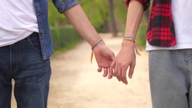 Igbt bileziği olan ve parkta el ele tutuşan iki gay 'in yakın çekim videosu.