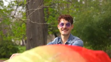 Parkta gökkuşağı hayranıyla dans eden sıradan, mutlu bir beyaz adam.