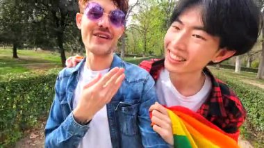 Parkta el sallayan ve sırtında taşıyarak eğlenen eşcinsel bir çiftin fotokopi çekilen yatay fotoğrafı.