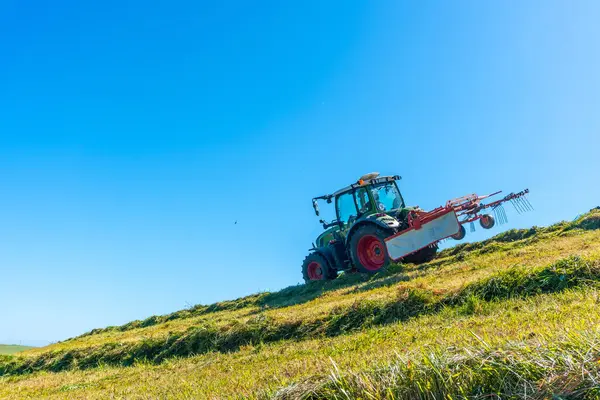 Sebuah Traktor Mengemudi Menuruni Bukit Membajak Rumput Langit Cerah Dan Stok Foto Bebas Royalti