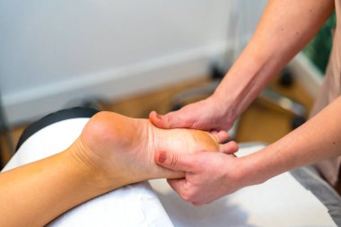 Close-up of an unrecognizable woman receiving a foot massage in the clinic clipart
