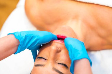 Bir masörün lateks eldivenleriyle ellerin yakın plan çekimleri bir kadına bruxism ve temporomandibular eklem bozukluğu için çene masajı yapar.