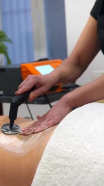 Tanımlanamayan bir fizyoterapistin INDIBA elektrikli aletini kullanarak bir hastanın sırtına baskı uygulayarak yakın plan görüntüsü.