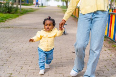 Tanımlanamayan Afrikalı anne ve bebek sokakta el ele yürüyorlar.