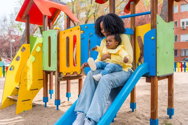 Glad Afrikansk Mor Med Baby Jente Fanget Glir Fargerik Lekeplass – stockfoto