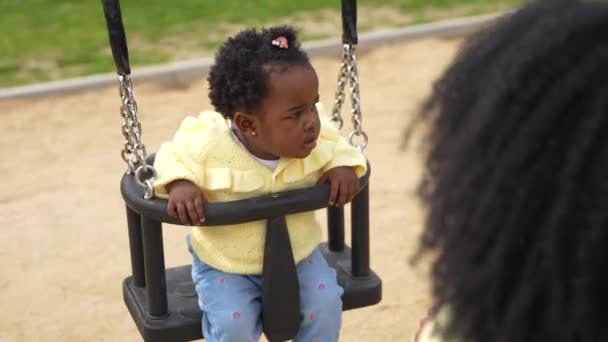 一个非洲女孩和一个难以辨认的母亲在公园里荡秋千的剪影 免版税图库视频