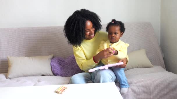 非洲母亲和孩子在家里画画 坐在客厅的沙发上 — 图库视频影像