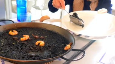 Karides ve kalamar ile siyah pirinç servis eden bir kaşık, bir kuru pilav, paella ya da kil tencerede pişirilmiş, Valencia Akdeniz mutfağının karakteristik bir tadında. İspanya