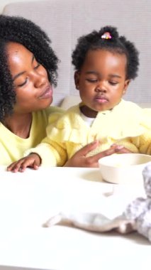 Afrikalı bir anne küçük kızını kucağında tutuyor ve evde duruyor.