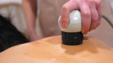 Sedyede yatan hasta klinikte şok dalgası alternatif terapi masajı yaptırıyor.