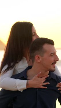 Gün batımında sahilde sevişen romantik bir çiftin yatay yakın plan fotoğrafı.