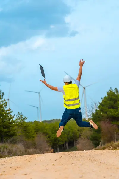 工人们在一个绿色能源公园的小径上跳跃和举起胳膊 免版税图库照片