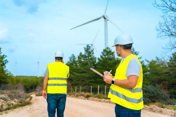 Techniciens Inspectant Des Éoliennes Dans Parc Énergie Verte Parler Mobile Photo De Stock