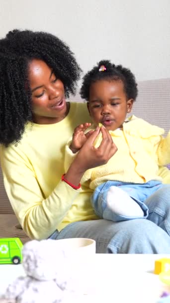 Afrikanisches Kleinkind Isst Wohnzimmer Neben Ihrer Lächelnden Mutter Hause — Stockvideo