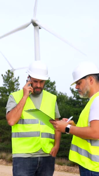 Two Male Colleagues Engineers Working Green Park Next Wind Turbines Ліцензійні Стокові Відео