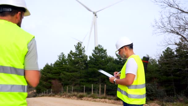 Rear View Male Mature Engineer Writing Notes Inspecting Wind Turbines Ліцензійні Стокові Відеоролики