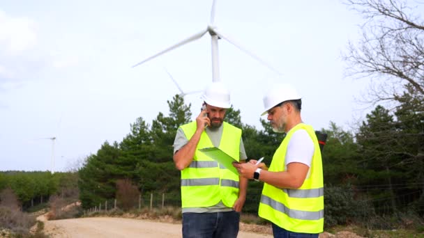 Two Male Colleagues Engineers Working Green Park Next Wind Turbines Стокове Відео 